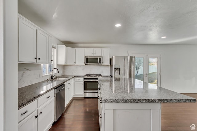 12756 S Diamond Back Dr W, Riverton, UT 84096 - kitchen featuring appliances with stainless steel finishes, tasteful backsplash, a kitchen island, sink, and white cabinetry