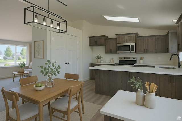 kitchen featuring a sink, stainless steel appliances, dark brown cabinets, vaulted ceiling, and light countertops