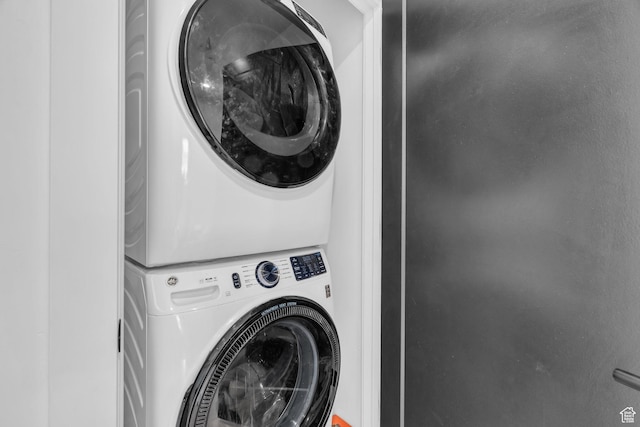 clothes washing area featuring stacked washing maching and dryer
