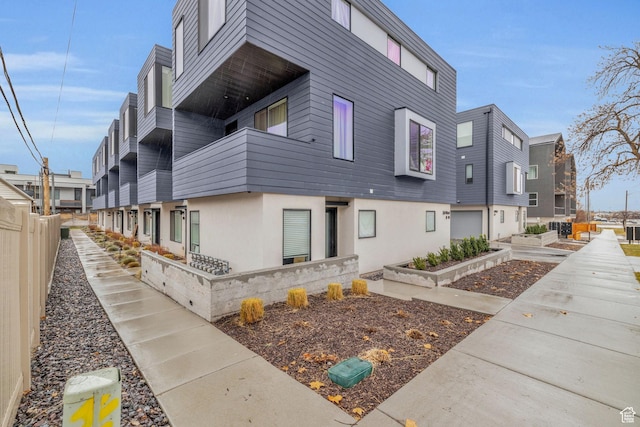 view of side of property with stucco siding, a balcony, and fence
