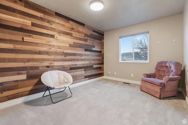 living area with wood walls and light colored carpet