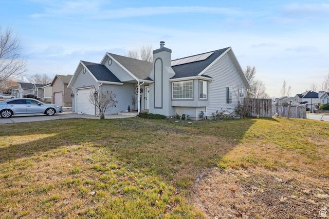 single story home with a garage, a front yard, and solar panels