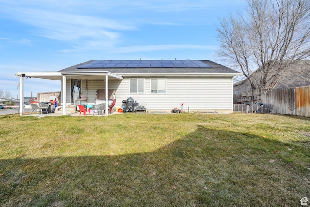 rear view of property with solar panels, a patio, and a lawn