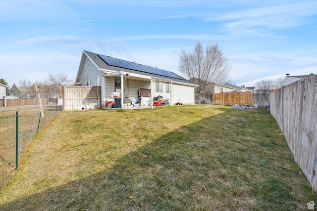 back of property featuring solar panels and a lawn