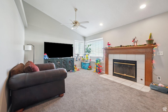 carpeted living room featuring ceiling fan, lofted ceiling, and a tiled fireplace