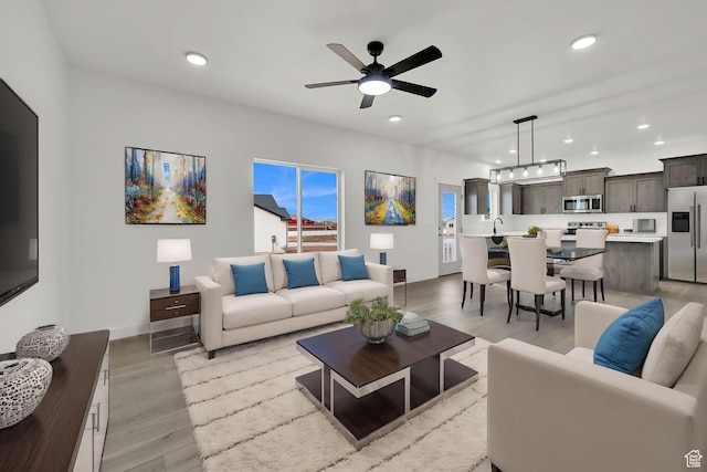 living room with light wood-style floors, baseboards, a ceiling fan, and recessed lighting