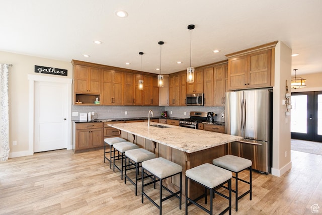 kitchen featuring pendant lighting, sink, an island with sink, a kitchen bar, and stainless steel appliances