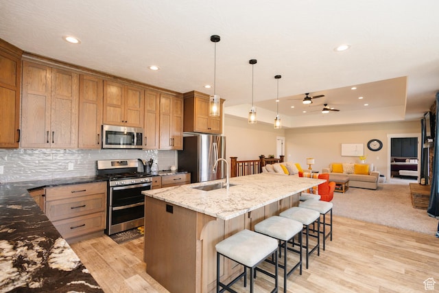 kitchen with a breakfast bar, sink, hanging light fixtures, dark stone countertops, and appliances with stainless steel finishes