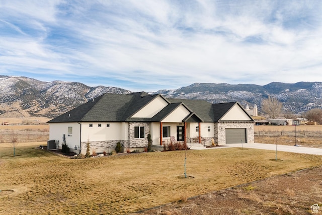 view of front of house featuring a mountain view, a garage, cooling unit, and a front yard