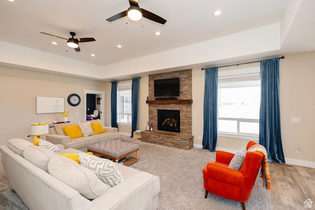 living room with a fireplace, a tray ceiling, ceiling fan, and light hardwood / wood-style floors