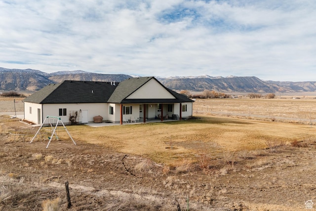 rear view of house featuring a mountain view, a rural view, and a patio area