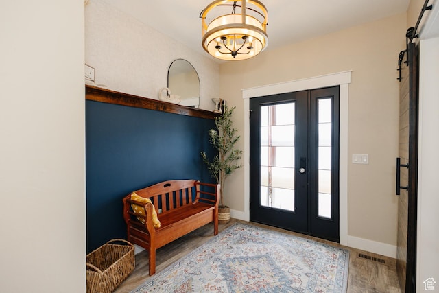 interior space featuring a barn door, light hardwood / wood-style flooring, and an inviting chandelier