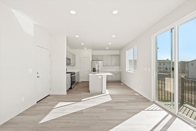 1367 N Harper Way Unit 0248, Tooele, UT 84074 - kitchen featuring stainless steel appliances, light wood-type flooring, light countertops, an island with sink, and recessed lighting