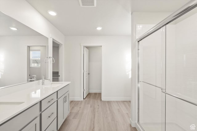 1367 N Harper Way Unit 0248, Tooele, UT 84074 - bathroom featuring a stall shower, wood finished floors, double vanity, and recessed lighting