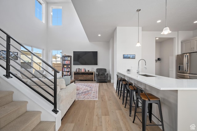 5629 S Adobe Sun Dr, St George, UT 84790 - interior space with kitchen peninsula, a breakfast bar, sink, decorative light fixtures, and stainless steel fridge with ice dispenser