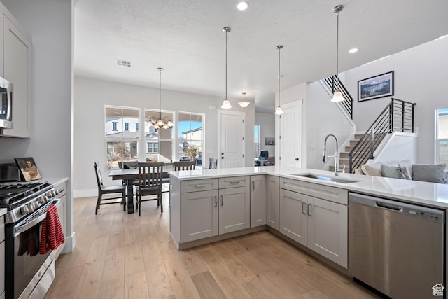 5629 S Adobe Sun Dr, St George, UT 84790 - kitchen featuring stainless steel appliances, sink, a notable chandelier, light hardwood / wood-style floors, and hanging light fixtures