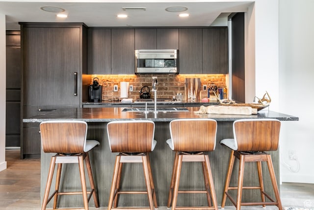 692 Main St Unit D, Park City, UT 84060 - kitchen featuring hardwood / wood-style floors, a kitchen breakfast bar, backsplash, and dark stone counters