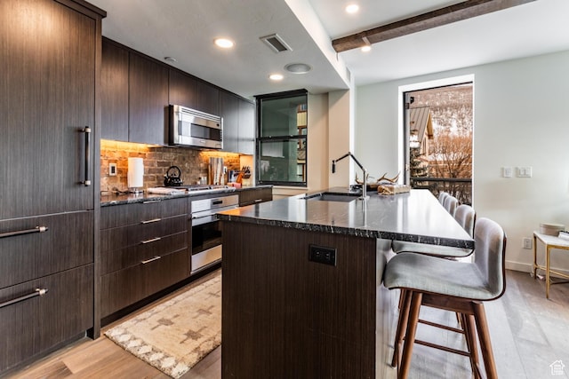 692 Main St Unit D, Park City, UT 84060 - kitchen with a breakfast bar, sink, an island with sink, beam ceiling, and stainless steel appliances