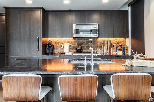 692 Main St Unit D, Park City, UT 84060 - kitchen with a kitchen bar, tasteful backsplash, dark stone counters, and stovetop