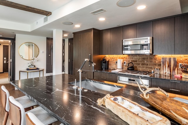 692 Main St Unit D, Park City, UT 84060 - kitchen featuring backsplash, sink, appliances with stainless steel finishes, a kitchen bar, and dark brown cabinetry