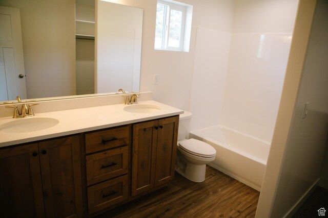 full bathroom with shower / bathing tub combination, vanity, wood-type flooring, and toilet