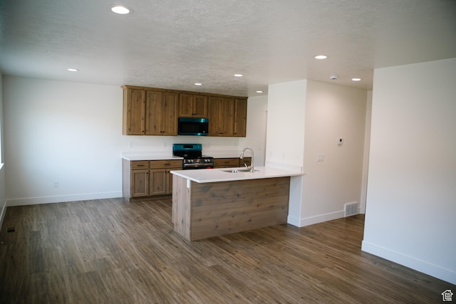 kitchen featuring sink, dark wood-type flooring, kitchen peninsula, a textured ceiling, and stainless steel stove