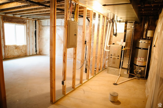 basement featuring electric panel and strapped water heater