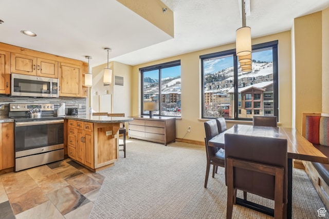 3855 Grand Summit Dr Unit 301, Park City, UT 84098 - kitchen featuring hanging light fixtures, stainless steel appliances, kitchen peninsula, a breakfast bar area, and decorative backsplash