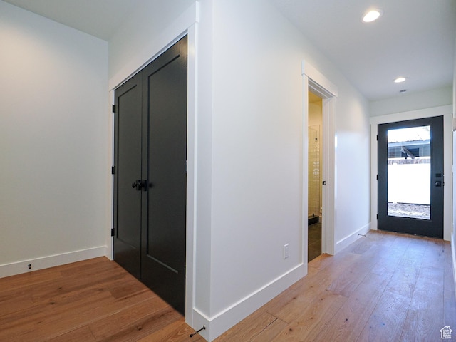 hallway featuring light wood-type flooring, baseboards, and recessed lighting