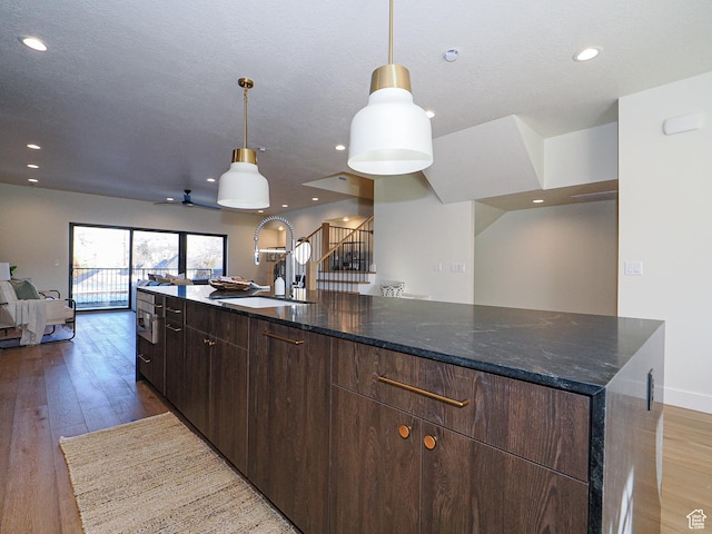 kitchen featuring a sink, open floor plan, recessed lighting, and light wood-style floors