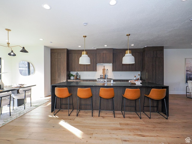 kitchen with recessed lighting, dark countertops, modern cabinets, and a kitchen breakfast bar