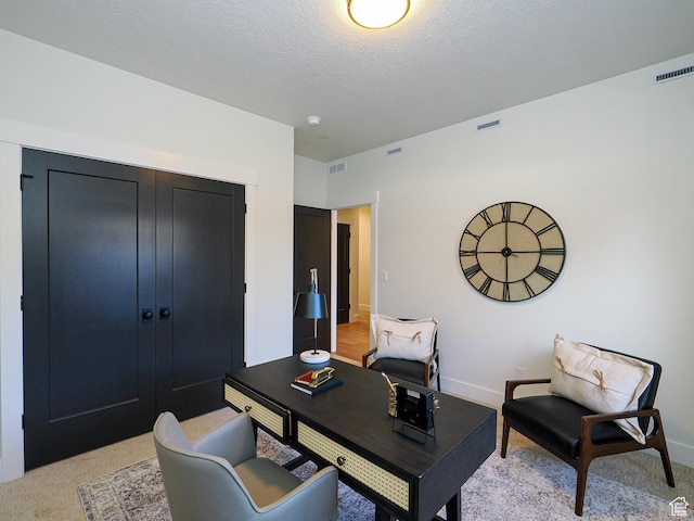 office space with visible vents, light colored carpet, and a textured ceiling