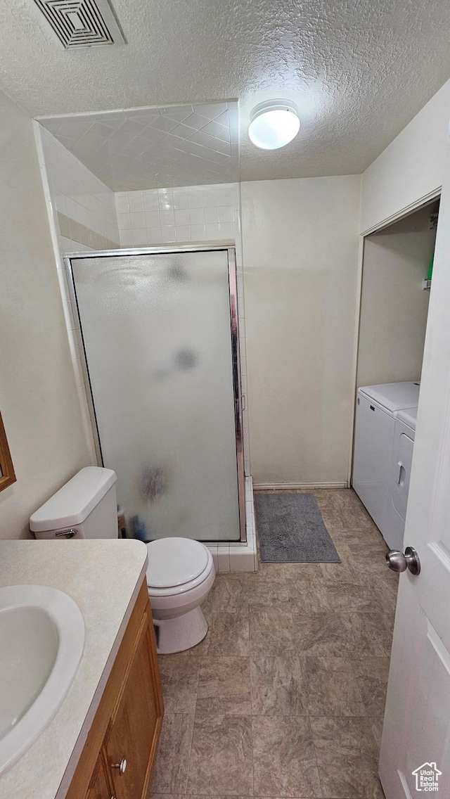 bathroom with walk in shower, a textured ceiling, vanity, washing machine and clothes dryer, and toilet