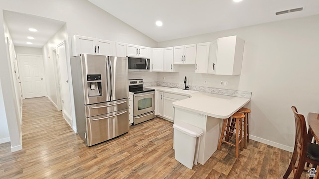 1303 N Riverside Ave Unit 36, Provo, UT 84604 - kitchen featuring appliances with stainless steel finishes, a peninsula, a kitchen bar, light wood-style flooring, and light countertops