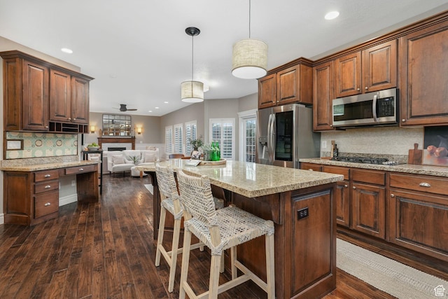 13234 S Lone Rock Dr E, Draper, UT 84020 - kitchen featuring a kitchen breakfast bar, appliances with stainless steel finishes, tasteful backsplash, decorative light fixtures, and a kitchen island