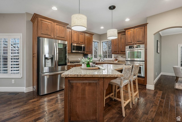 13234 S Lone Rock Dr E, Draper, UT 84020 - kitchen with light stone countertops, appliances with stainless steel finishes, decorative light fixtures, a kitchen island, and dark hardwood / wood-style flooring