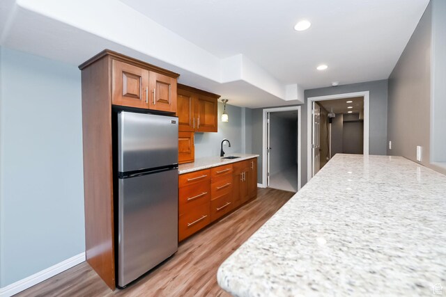 3568 N 500 E, North Ogden, UT 84414 - kitchen with freestanding refrigerator, a sink, wood finished floors, brown cabinetry, and light stone counters