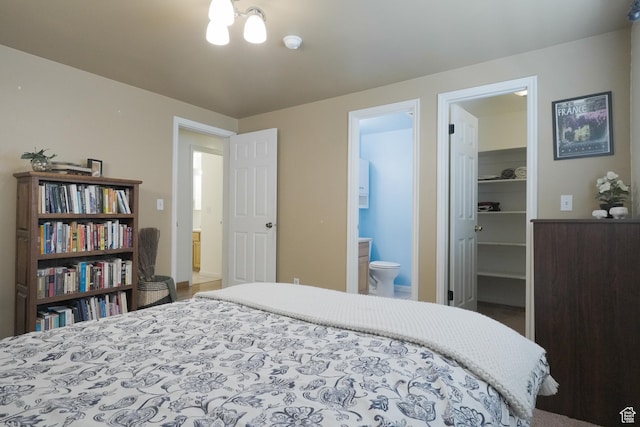 bedroom featuring ensuite bath, a spacious closet, a closet, and an inviting chandelier