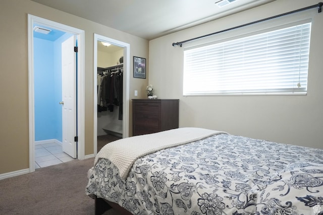 carpeted bedroom featuring multiple windows, a walk in closet, ensuite bath, and a closet