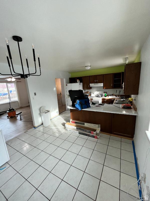 kitchen with kitchen peninsula, stainless steel electric range oven, dark brown cabinets, and light tile patterned floors