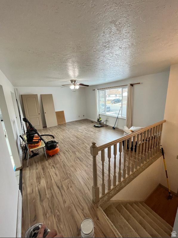 living room with ceiling fan, wood-type flooring, and a textured ceiling