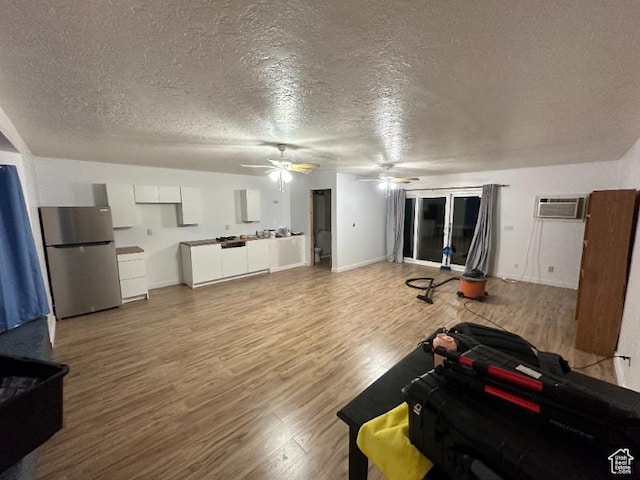 living room featuring a wall mounted AC, hardwood / wood-style floors, and a textured ceiling