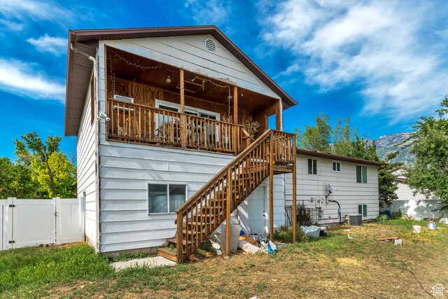 back of property with a yard and central AC