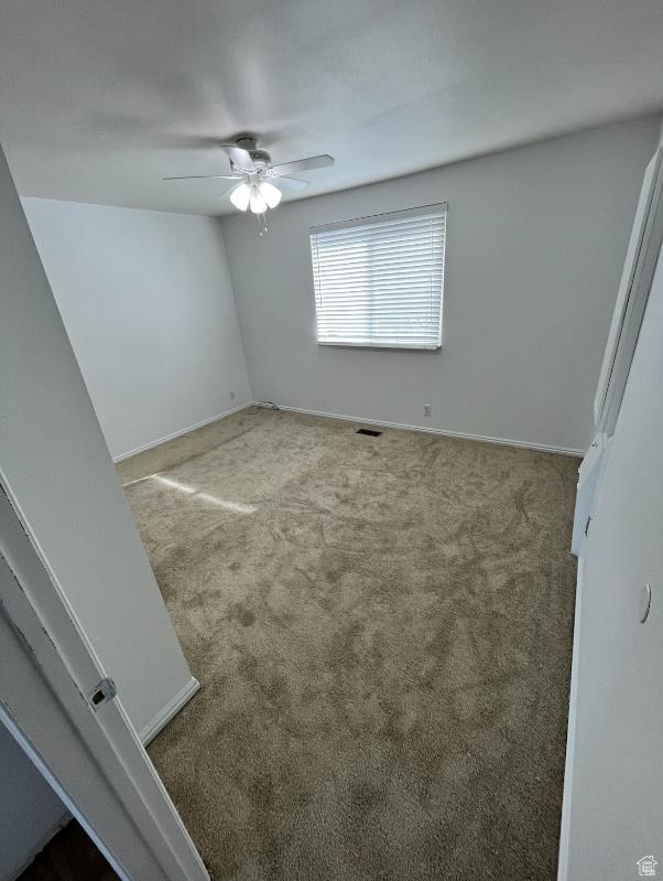 carpeted spare room with ceiling fan