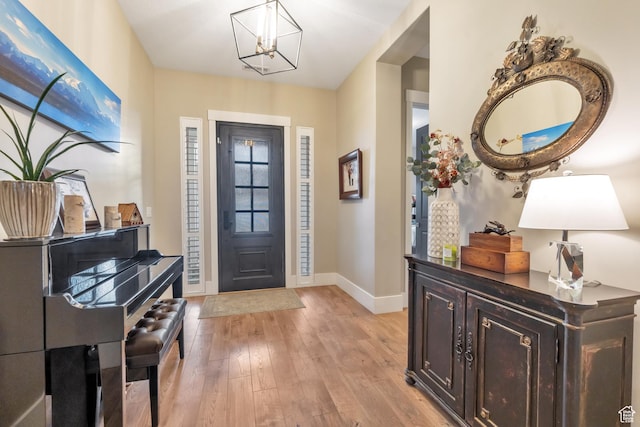 entrance foyer featuring light wood-style flooring, baseboards, and a notable chandelier