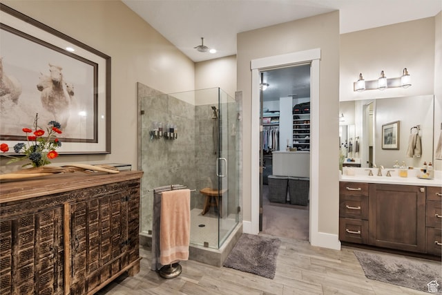 bathroom featuring a stall shower, wood finished floors, vanity, and a walk in closet