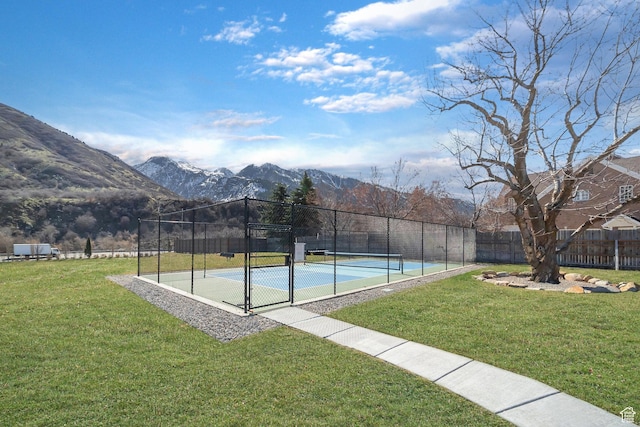 exterior space featuring a yard, a mountain view, a tennis court, and fence