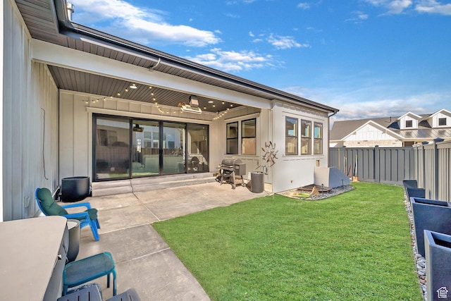 back of property with fence, a patio, and a lawn