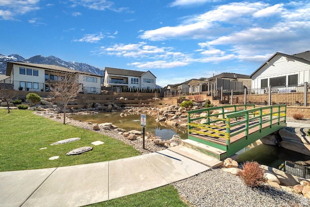 view of home's community with a yard, a mountain view, fence, and a residential view