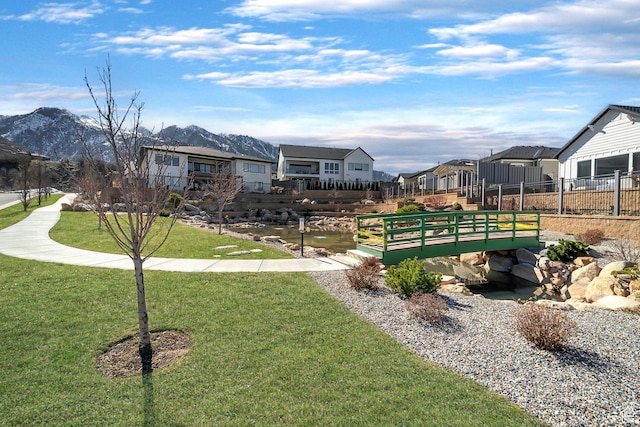 view of community featuring a mountain view, fence, a residential view, and a lawn